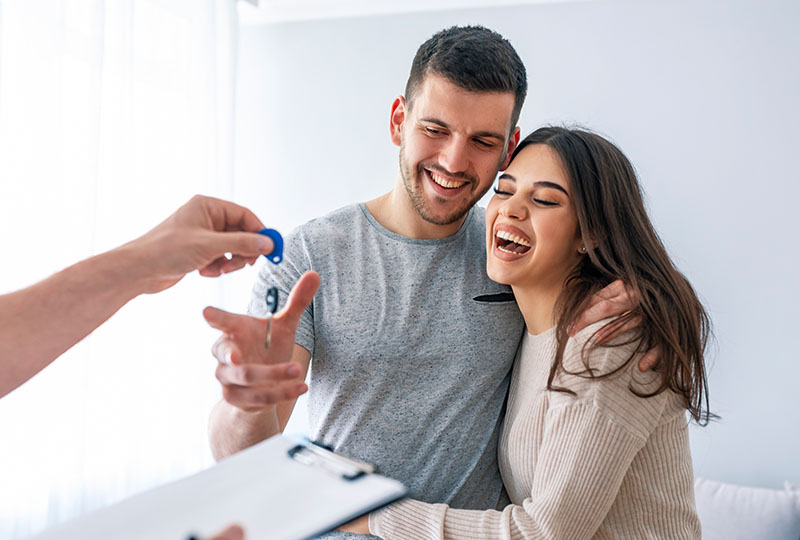 Happy couple receiving keys after buying their first home